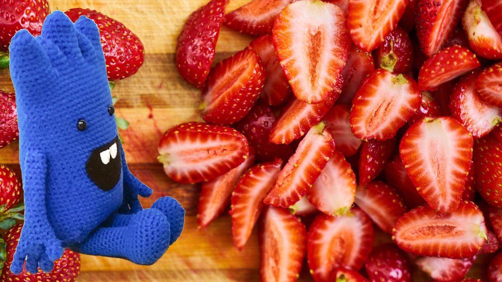 MrBlue sitzt inmitten frischer Erdbeeren.